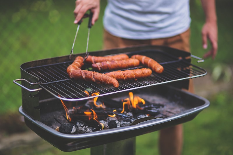 summer safety tips - man grilling hot dogs