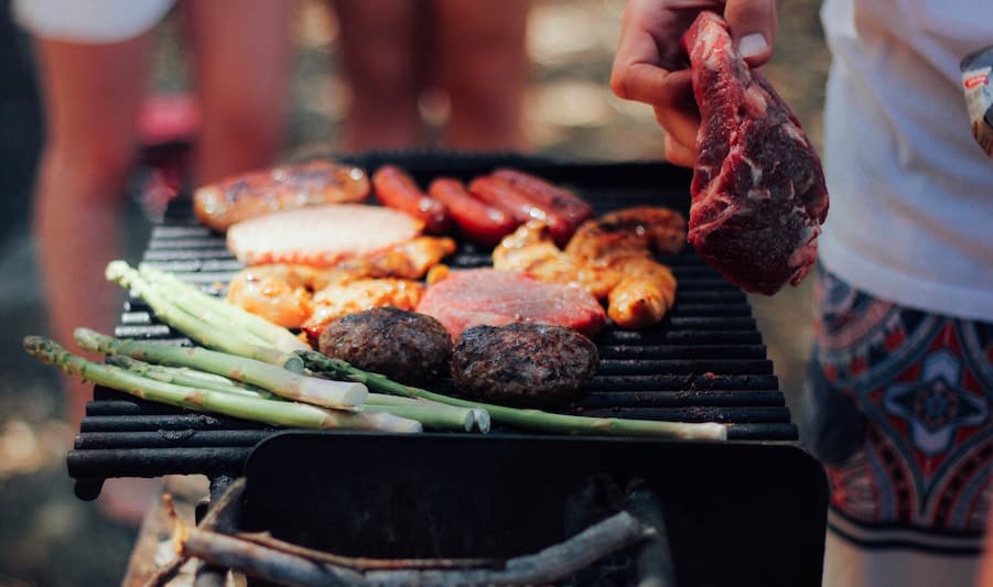 person grilling meat and veggies - food safety to prevent foodborne illness