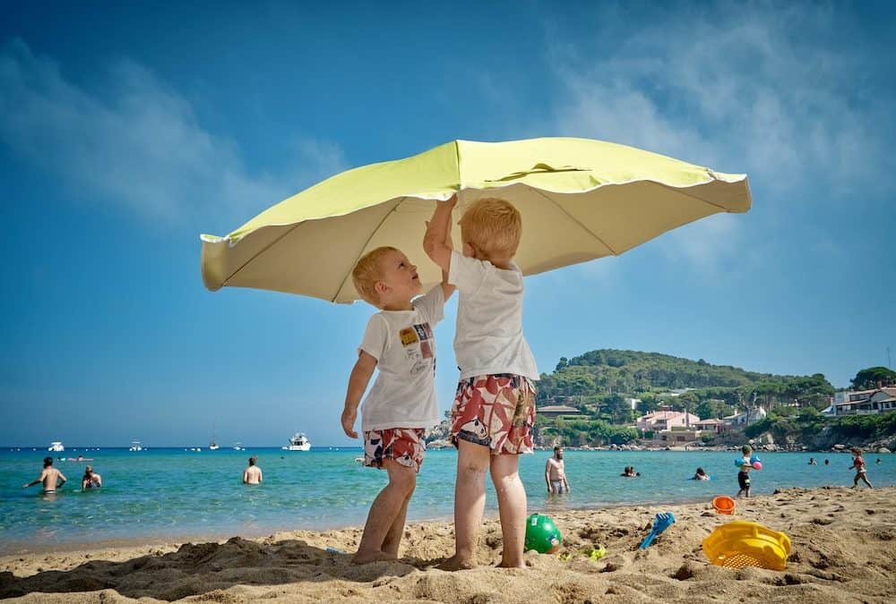 young boys under beach umbrella to prevent sunburn